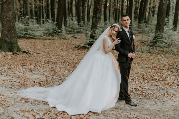 Beautiful bride in a long white dress. Handsome groom in a black suit. Couple in a summer park