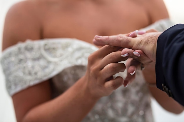 beautiful bride in a luxurious dress puts a wedding ring on her grooms finger at the wedding