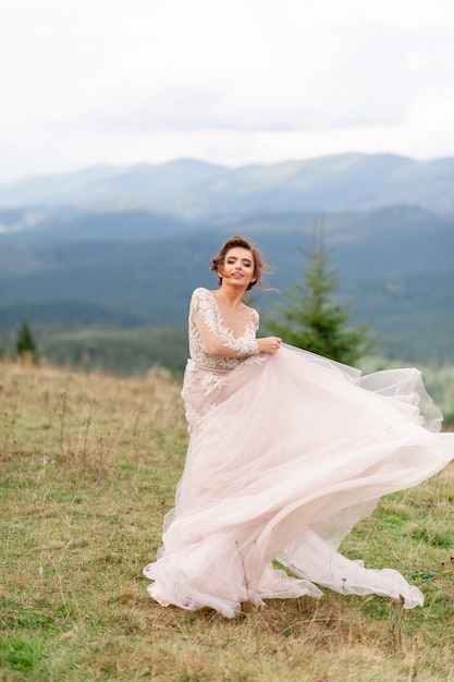 Beautiful bride posing in her wedding dress on a background of mountains.