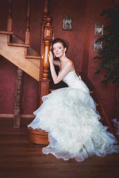 Beautiful bride sitting on wooden stairs