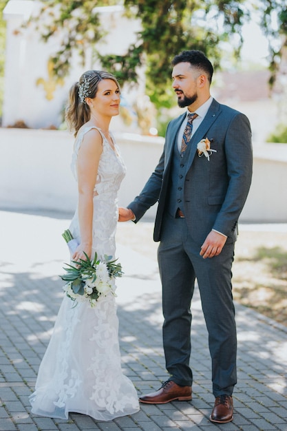 Beautiful bride in a wedding dress and a groom in a stylish suit are having a photoshoot in the park