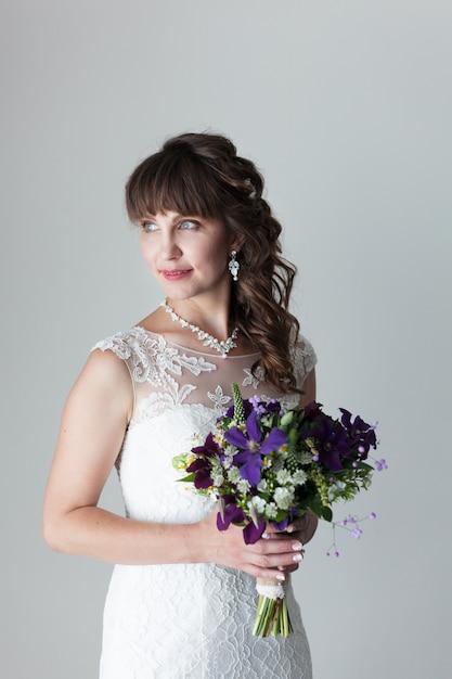 Beautiful bride in white lace dress with a bouquet of flowers