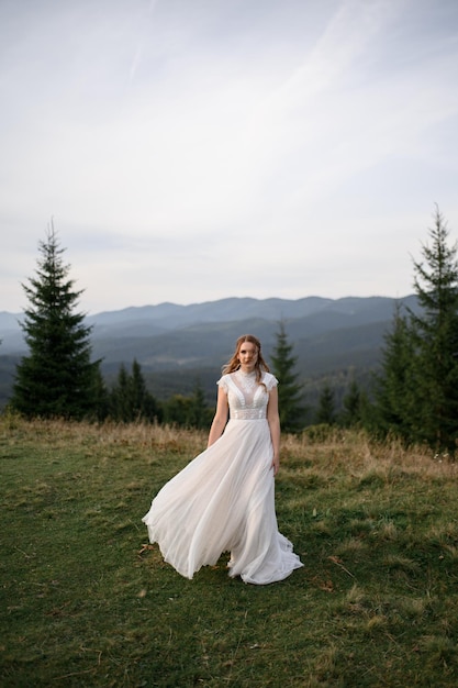 Beautiful bride in a white wedding dress on a background of mountains