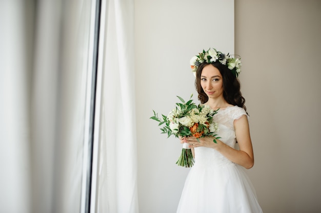 Beautiful bride with a bouquet of flowers and a wreath on her head.