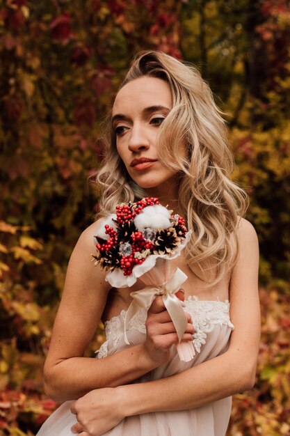 Beautiful bride with a bouquet in her hands Wedding in autumn in the forest