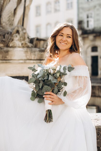 Beautiful bride with a bouquet posing in the city streets