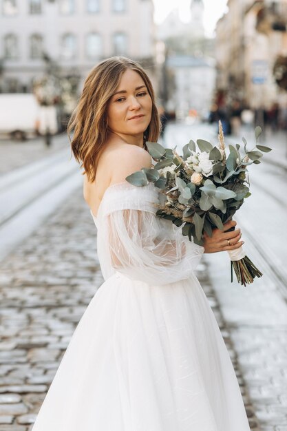 Beautiful bride with a bouquet posing in the city streets