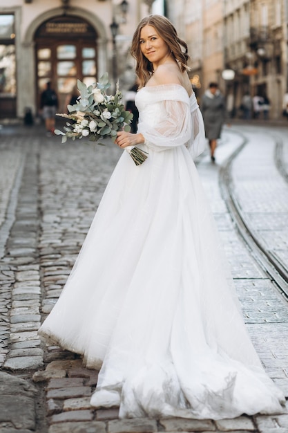 Beautiful bride with a bouquet posing in the city streets