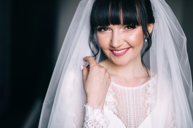 Beautiful bride with fashionable wedding hairstyle Close up portrait of young gorgeous bride in white dress with veil