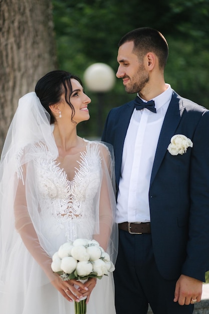 Beautiful bride with her handsome groom walking outside on theri wedding day Happy newlyweds