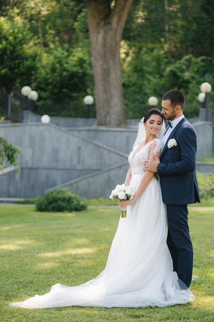 Beautiful bride with her handsome groom walking outside on theri wedding day Happy newlyweds