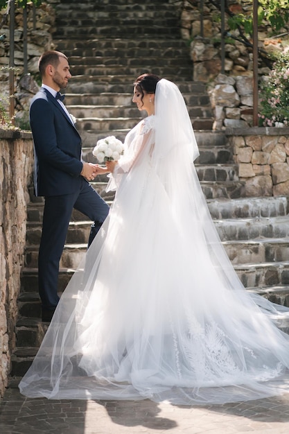 Beautiful bride with her handsome groom walking outside on theri wedding day Happy newlyweds