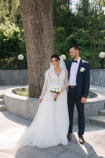 Beautiful bride with her handsome groom walking outside on theri wedding day Happy newlyweds