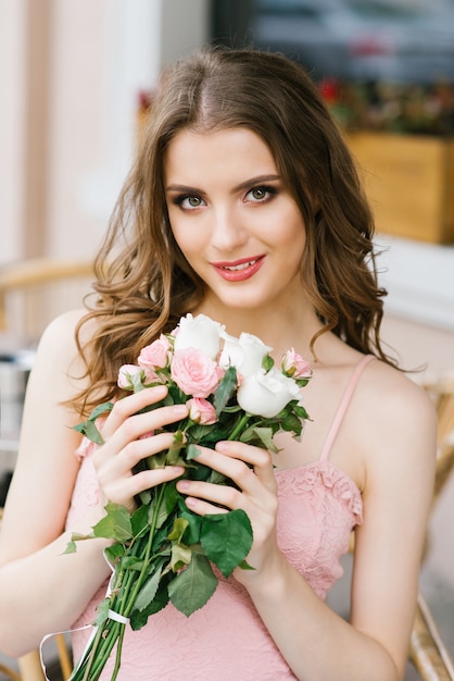 Beautiful brown-haired young girl with a bouquet of roses, professional makeup and styling. 