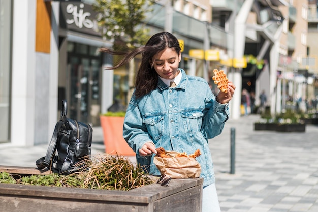 Beautiful brunette 20-30s enjoying delicious food from takeaway restaurant in the street in the lunchtime