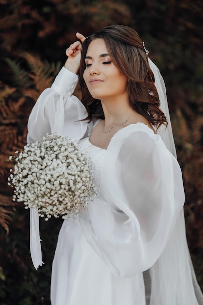 Beautiful brunette bride with a wreath of flowers Young girl is standing and holding a bouquet