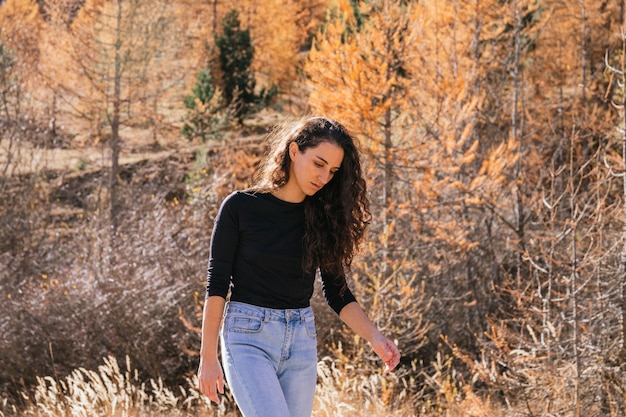 Beautiful brunette caucasian girl with long curly hair walks in the mountains