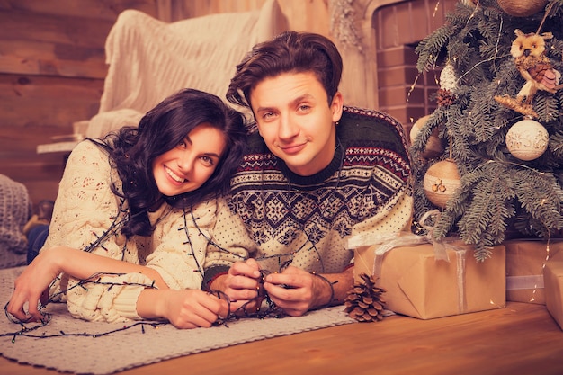 Beautiful brunette caucasian romantic loving couple in cozy warm sweaters in the cabin on a christmas new year eve