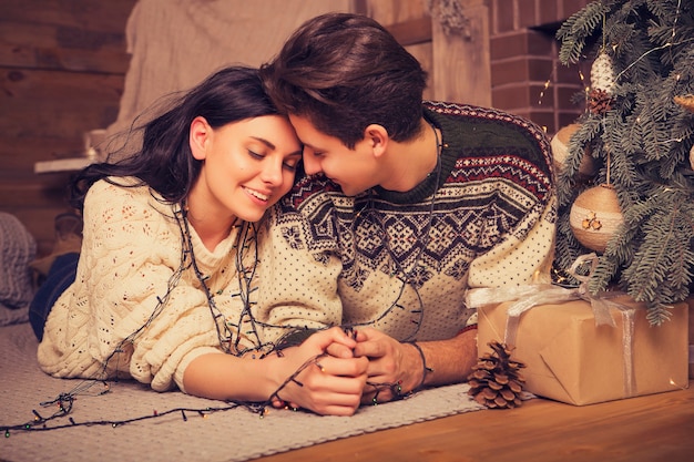 Beautiful brunette caucasian romantic loving couple in cozy warm sweaters in the cabin on a christmas new year eve