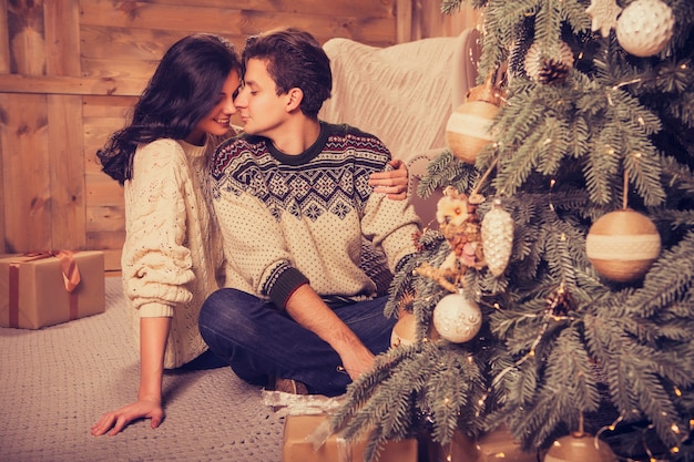 Beautiful brunette caucasian romantic loving couple in cozy warm sweaters in the cabin