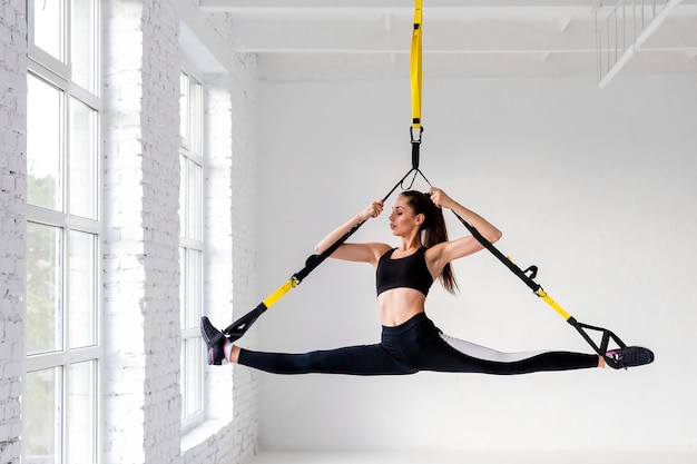 Beautiful brunette doing splits on  loops indoors.