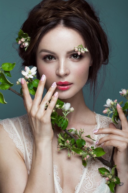 Beautiful brunette girl  with a gentle romantic makeup pink lips and flowers