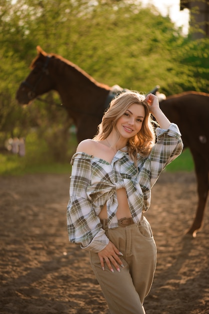 Beautiful brunette girl with her horse outdoors