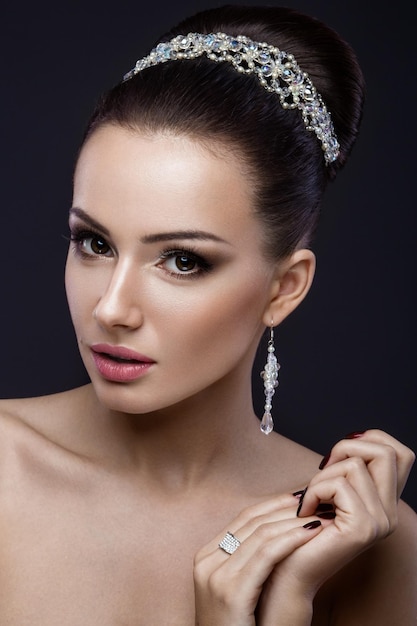 Beautiful brunette girl with perfect skin evening makeup wedding hairstyle and accessories Beauty face