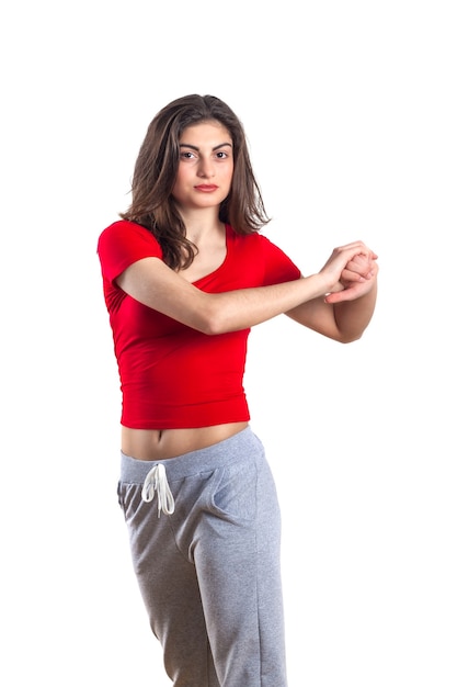 Beautiful brunette teenager in red shirt is exercising, white background.