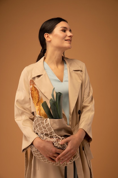 Beautiful brunette with a bag of groceries after shopping on a beige background