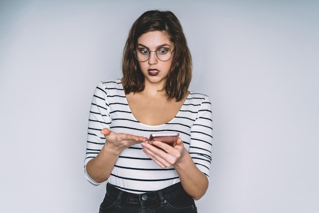 Beautiful brunette with dazed face pointing on smartphone