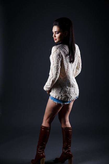 Beautiful brunette woman in beige sweater and blue shorts