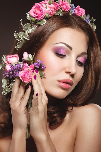 Beautiful brunette woman iwith a gentle romantic makeup pink lips holding flowers The beauty of the face