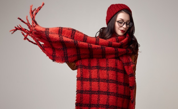 Beautiful brunette woman in sweater, glasses and red hat with big knitted scarf