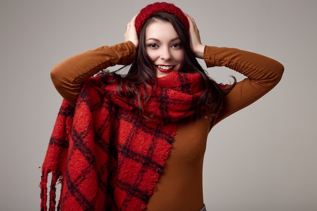 Beautiful brunette woman in sweater and red hat with big knitted scarf