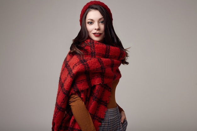 Beautiful brunette woman in sweater and red hat with big knitted scarf