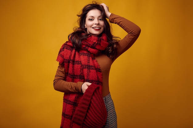 Beautiful brunette woman in sweater and red hat with big knitted scarf