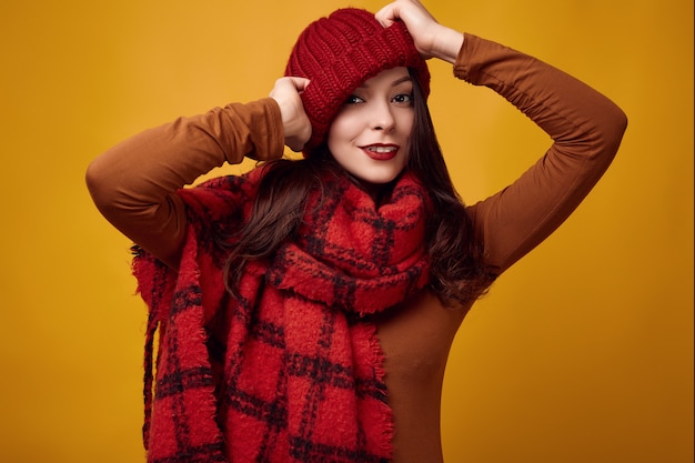 Beautiful brunette woman in sweater and red hat with big knitted scarf