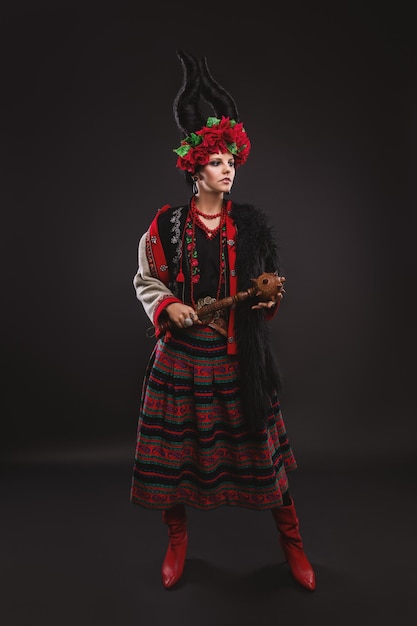 beautiful brunette woman in a traditional Ukrainian costume with a floral wreath and horns