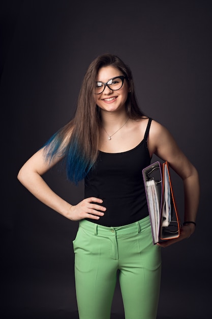 Beautiful brunette young woman in glasses and green pants with folders