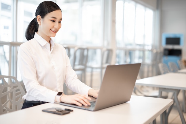 beautiful business asian woman with suit working in office desk using computer with copy space