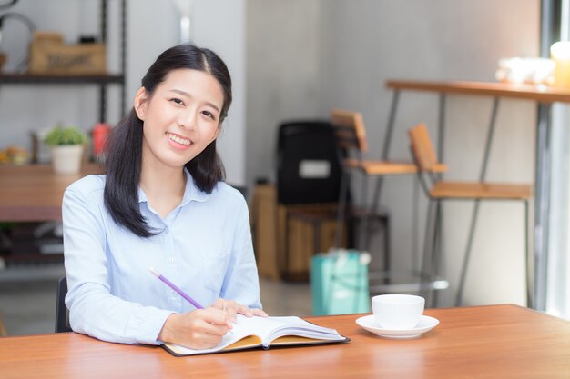 Beautiful business asian woman writing on notebook on table