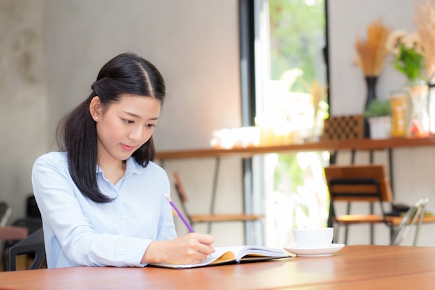 Beautiful business asian young woman writing on notebook on table.