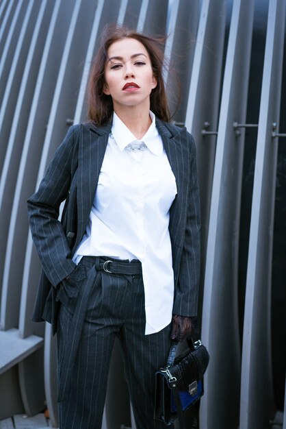 A beautiful business woman of caucasian ethnicity in a business suit and white shirt is posing fashi...