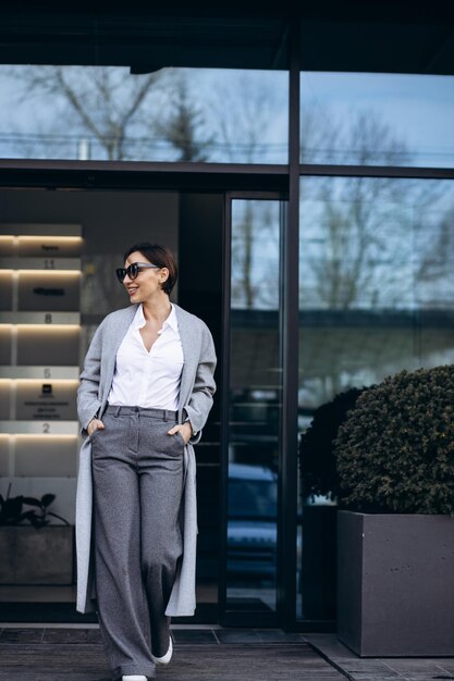 Photo beautiful business woman in grey coat outside office building