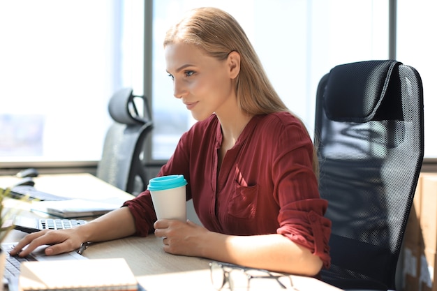 Beautiful business woman in smart casual wear working on laptop in the office.