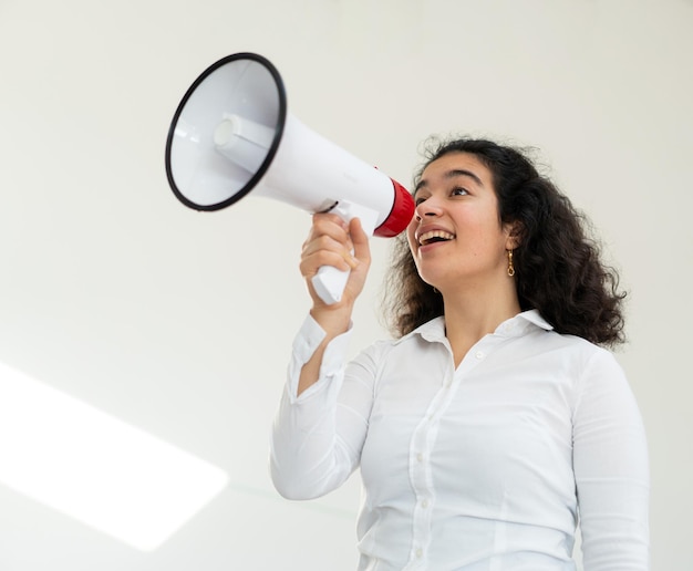 Beautiful business woman with curly hair holding a megaphone. High quality photo