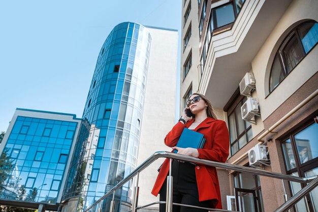 A beautiful business woman with a mobile phone is walking in the buildings in the city center