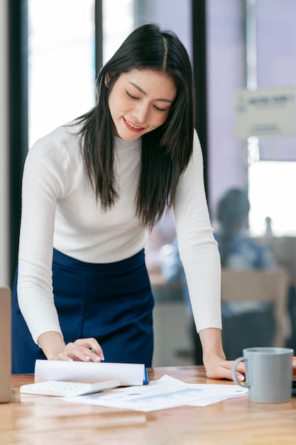 Beautiful businesswoman checking on paperwork standing at modern office