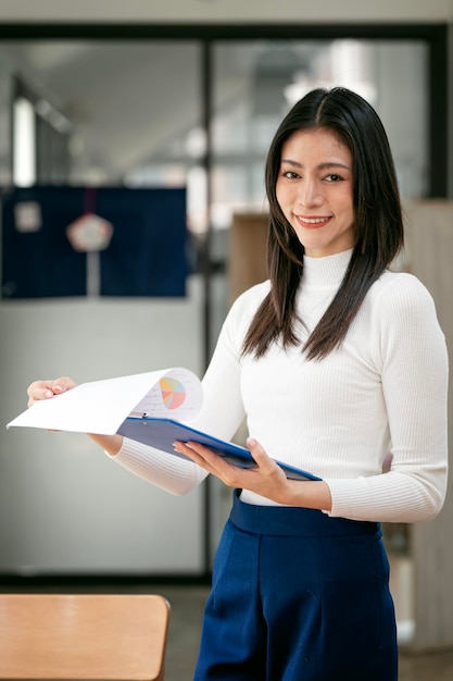 Beautiful businesswoman checking on paperwork standing at modern office